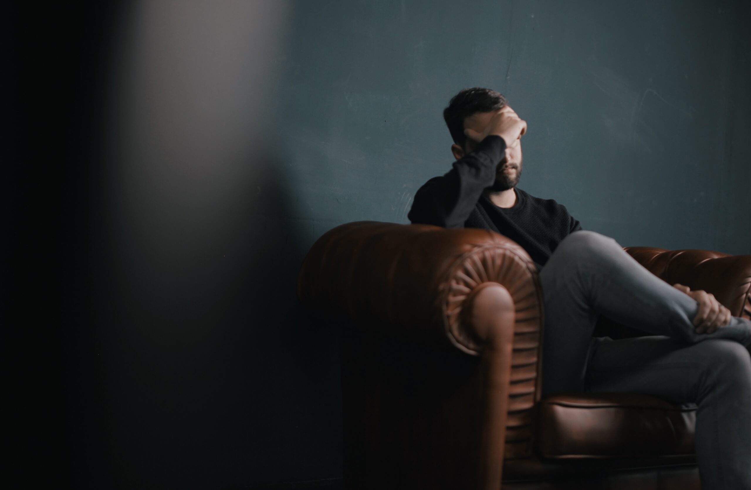 man siting on couch with head in one hand